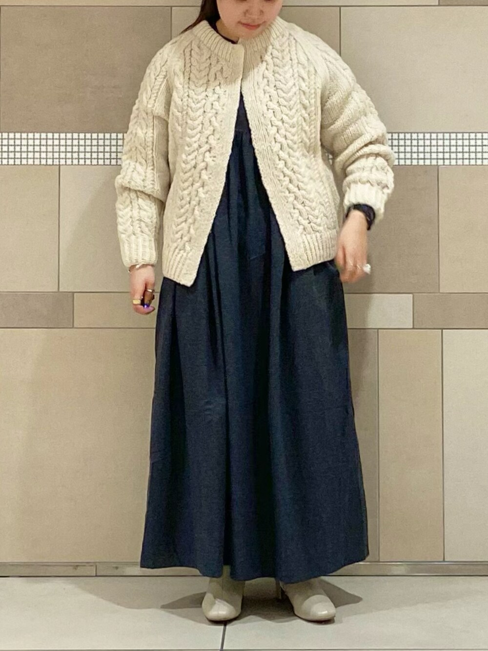 ホワイト系のブーツ、ホワイト系のニット/セーター、ブラック系のワンピースを着用したレディースの秋コーディネートの2枚目の写真