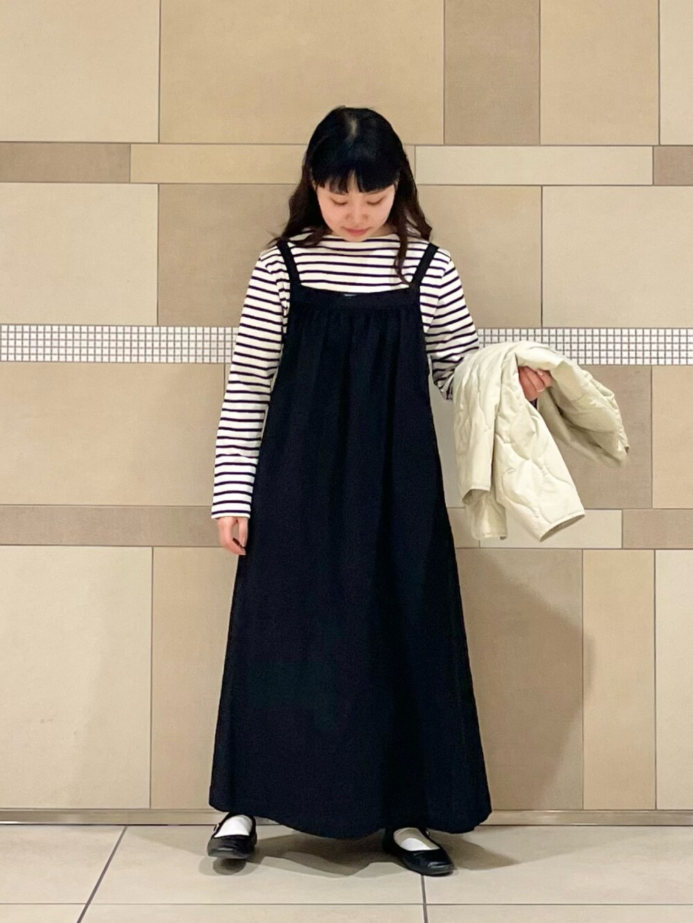 ベージュ系のダウンジャケット/コート、ブラック系のワンピース、ホワイト系のTシャツ/カットソーを着用したレディースの冬コーディネートの4枚目の写真