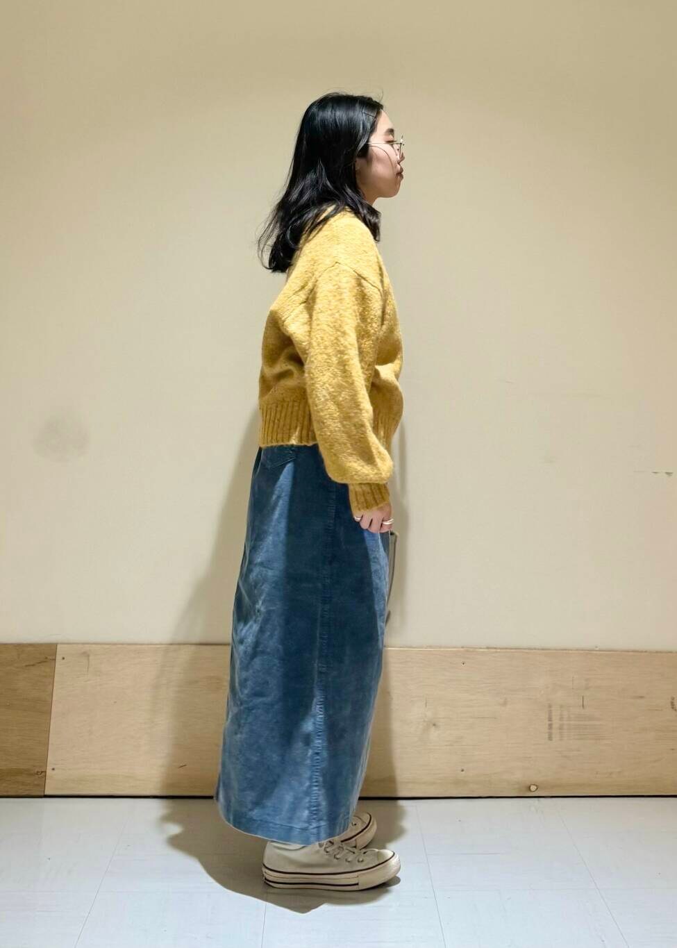 ベージュ系のトートバッグ、イエロー系のニット/セーター、ブルー系のスカートを着用したレディースの冬コーディネートの2枚目の写真