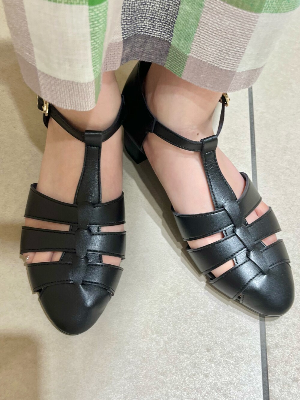 ベージュ系のベスト、ブラック系のタンクトップ、グリーン系のスカートを着用したレディースの春コーディネートの5枚目の写真