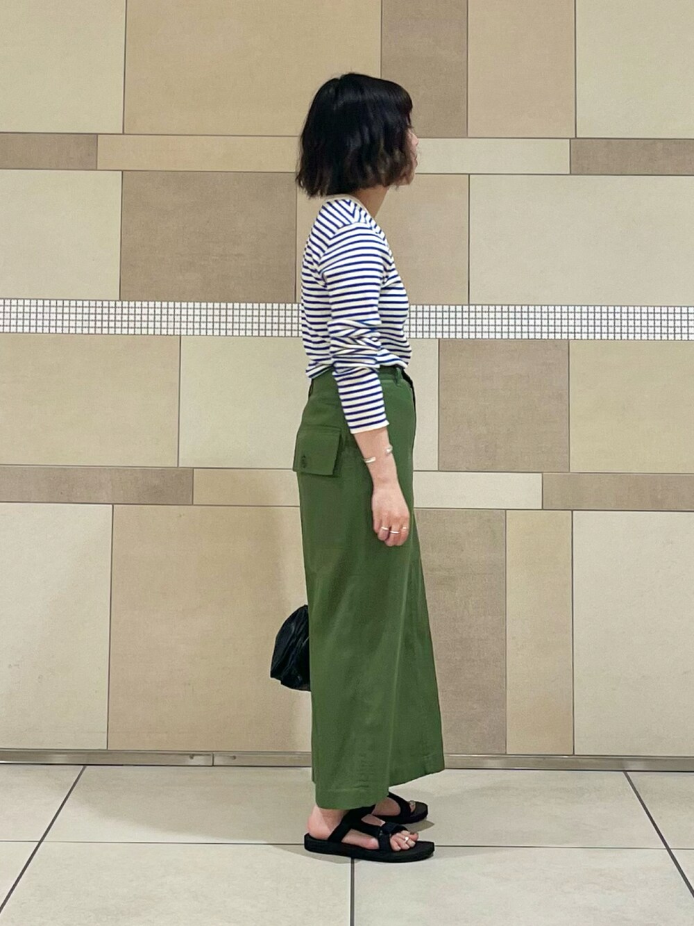 グリーン系のスカート、ブルー系のTシャツ/カットソー、ブラック系のサンダルを着用したレディースの夏コーディネートの3枚目の写真