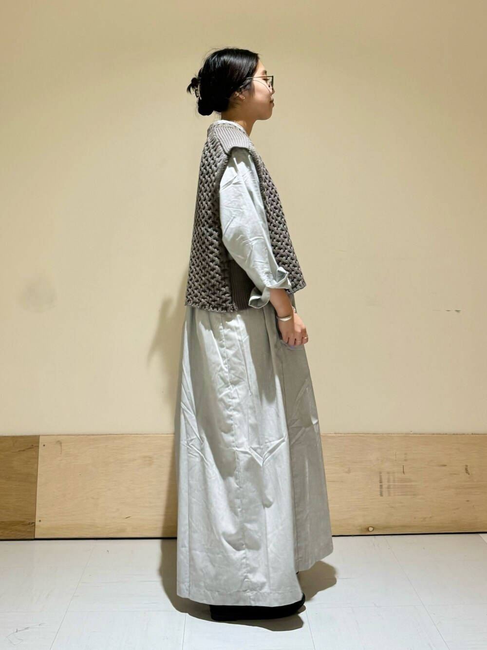 グレー系のベスト、ホワイト系のトートバッグ、ブラック系のバレエシューズを着用したレディースの秋コーディネートの2枚目の写真