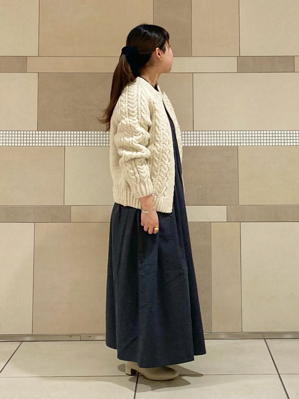 ホワイト系のブーツ、ホワイト系のニット/セーター、ブラック系のワンピースを着用したレディースの秋コーディネートの3枚目の写真