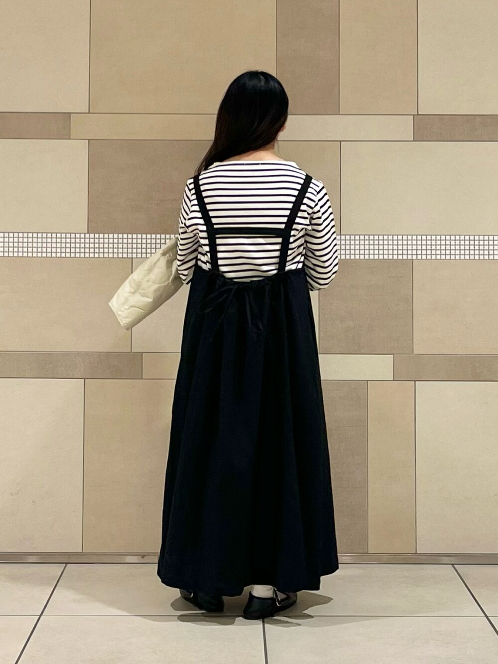 ベージュ系のダウンジャケット/コート、ブラック系のワンピース、ホワイト系のTシャツ/カットソーを着用したレディースの冬コーディネートの5枚目の写真