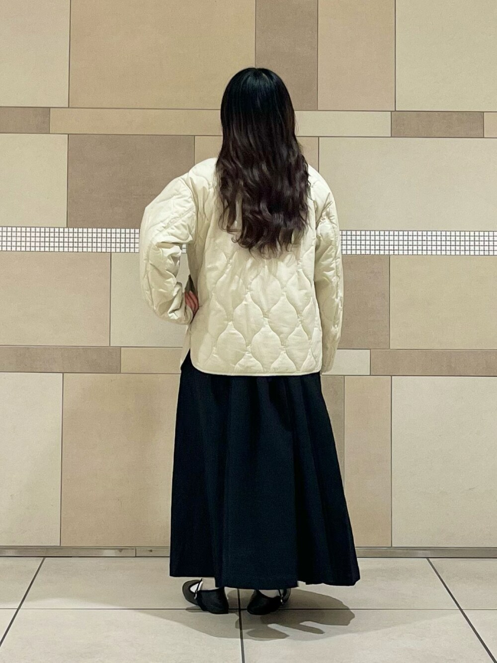 ベージュ系のダウンジャケット/コート、ブラック系のワンピース、ホワイト系のTシャツ/カットソーを着用したレディースの冬コーディネートの3枚目の写真