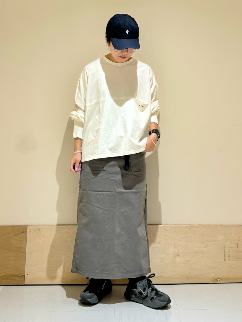 グレー系のスカート、ホワイト系のTシャツ/カットソーを着用したレディースの秋コーディネートの2枚目の写真