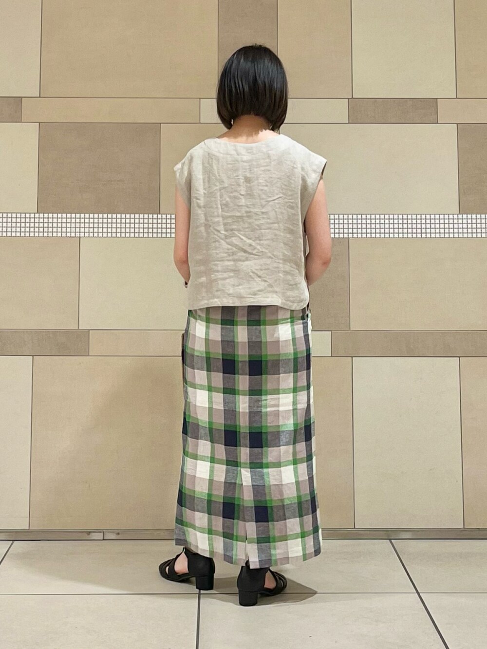 ベージュ系のベスト、ブラック系のタンクトップ、グリーン系のスカートを着用したレディースの春コーディネートの4枚目の写真