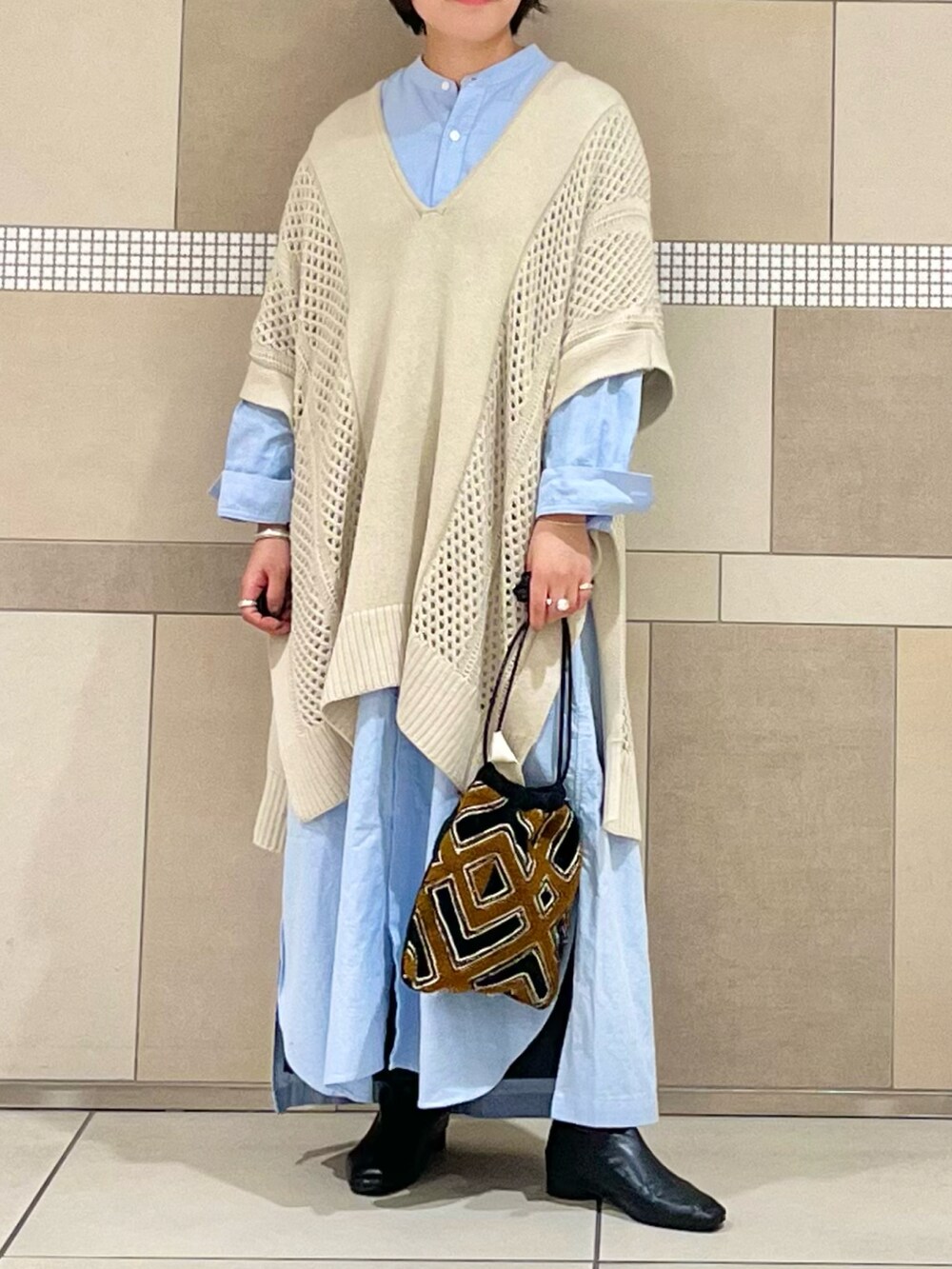 ベージュ系のニット/セーター、ブルー系のワンピース、ブラック系のスカートを着用したレディースの秋コーディネートの2枚目の写真