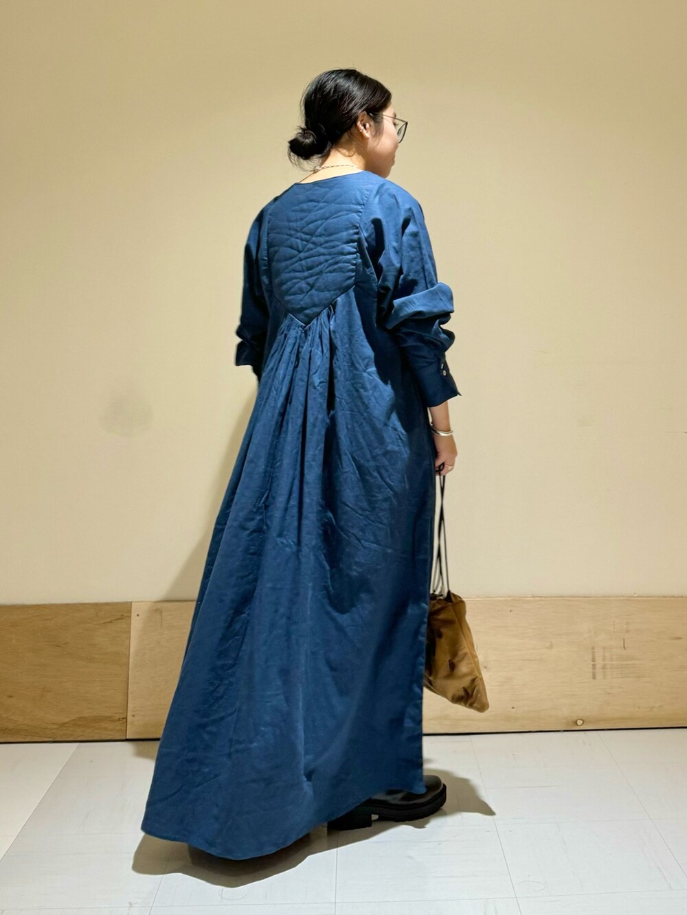 ブラック系のブーツ、ブラウン系のショルダーバッグ、ブルー系のワンピースを着用したレディースの秋コーディネートの3枚目の写真