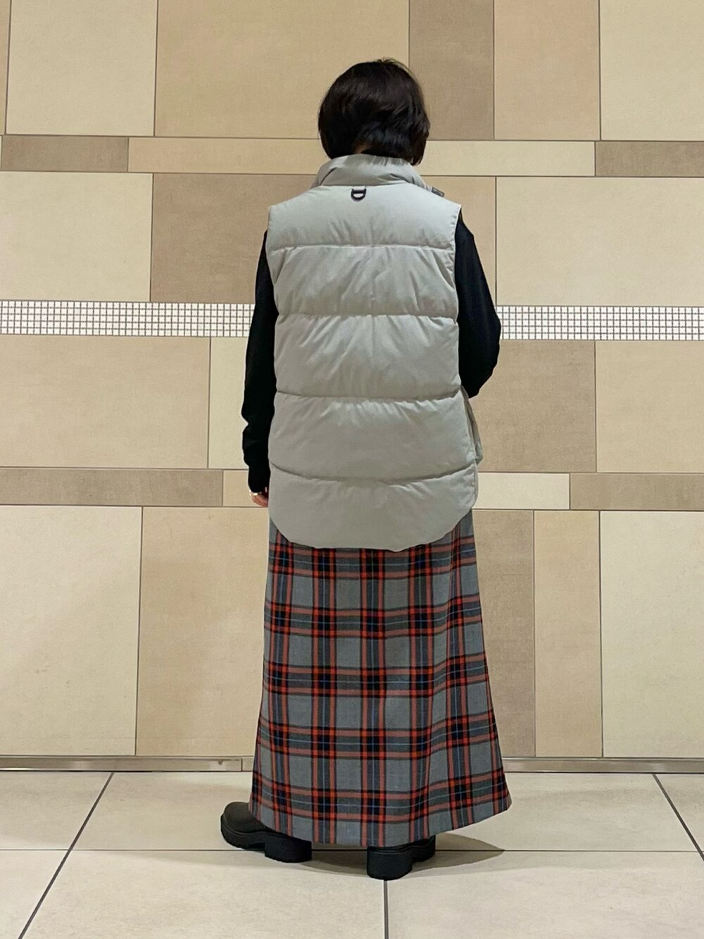 グレー系のダウンベスト、ブラック系のTシャツ/カットソー、グレー系のスカートを着用したレディースの秋コーディネートの4枚目の写真