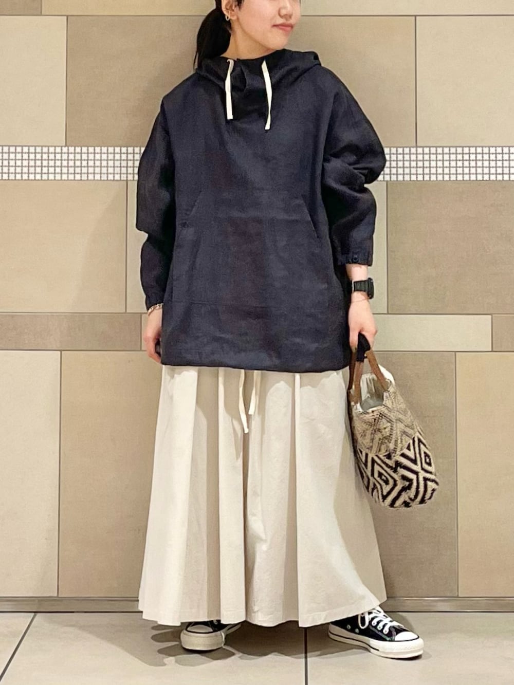 ブラック系のその他アウター、ホワイト系のスカート、ブラック系のトートバッグを着用したレディースの春コーディネートの2枚目の写真