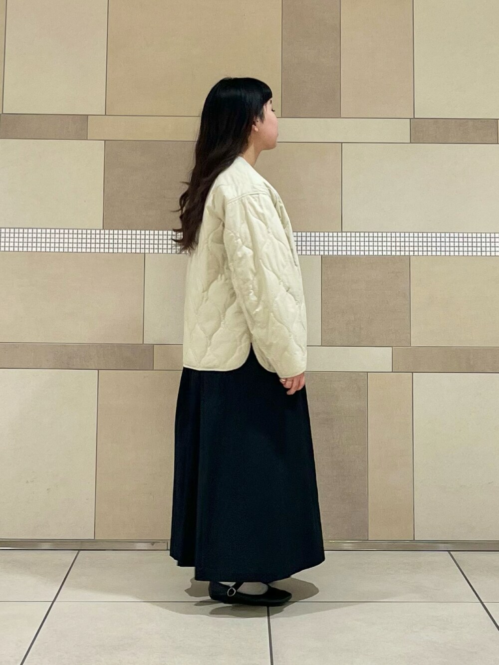 ベージュ系のダウンジャケット/コート、ブラック系のワンピース、ホワイト系のTシャツ/カットソーを着用したレディースの冬コーディネートの2枚目の写真