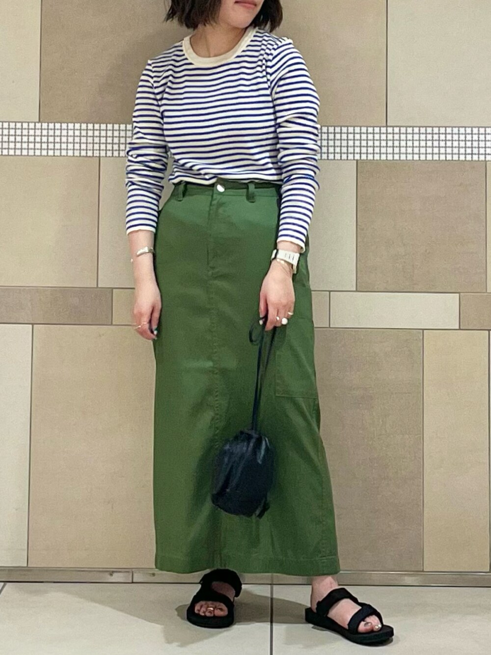 グリーン系のスカート、ブルー系のTシャツ/カットソー、ブラック系のサンダルを着用したレディースの夏コーディネートの2枚目の写真