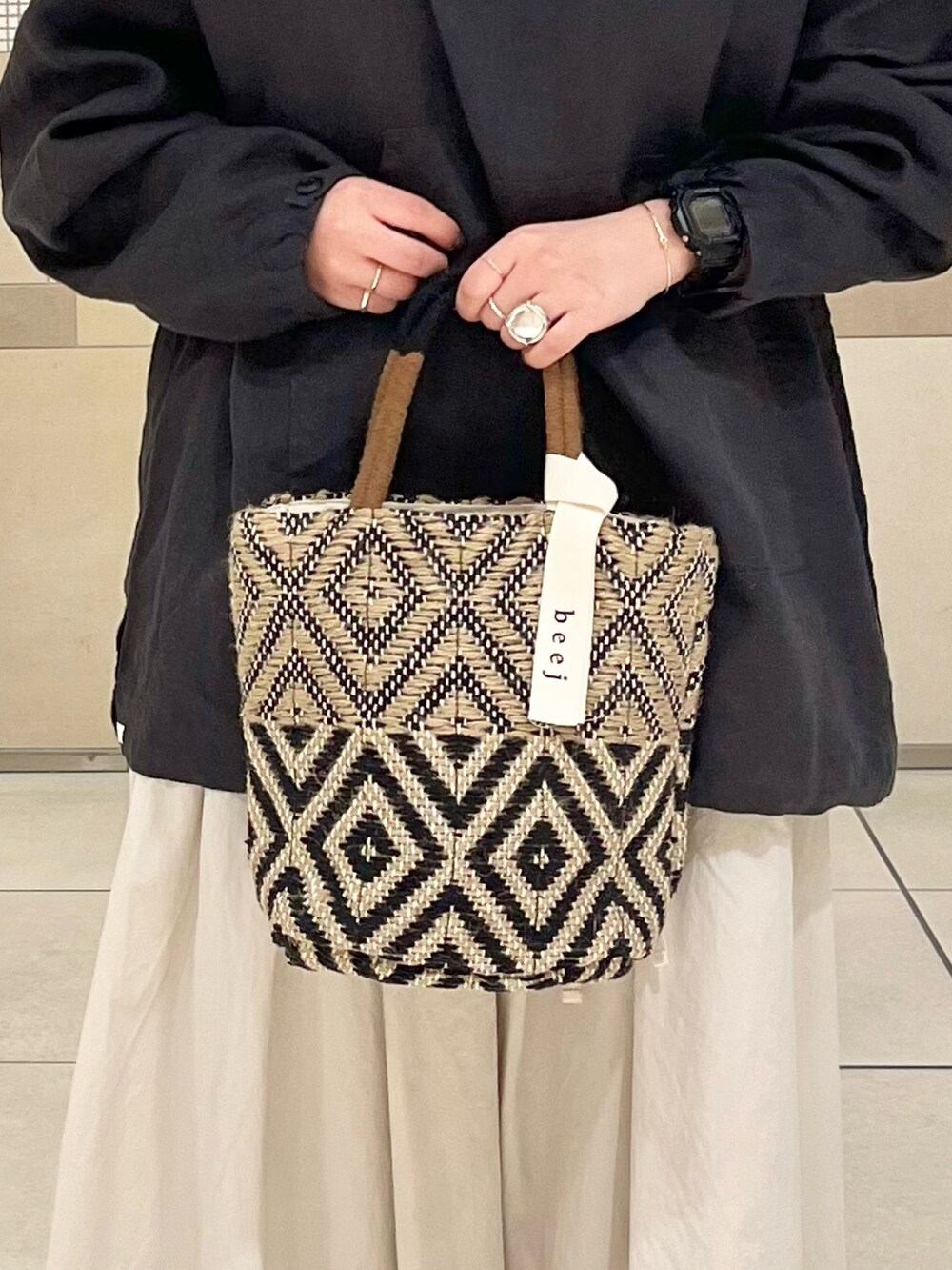 ブラック系のその他アウター、ホワイト系のスカート、ブラック系のトートバッグを着用したレディースの春コーディネートの5枚目の写真