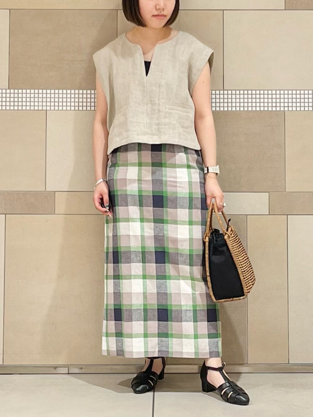 ベージュ系のベスト、ブラック系のタンクトップ、グリーン系のスカートを着用したレディースの春コーディネートの2枚目の写真