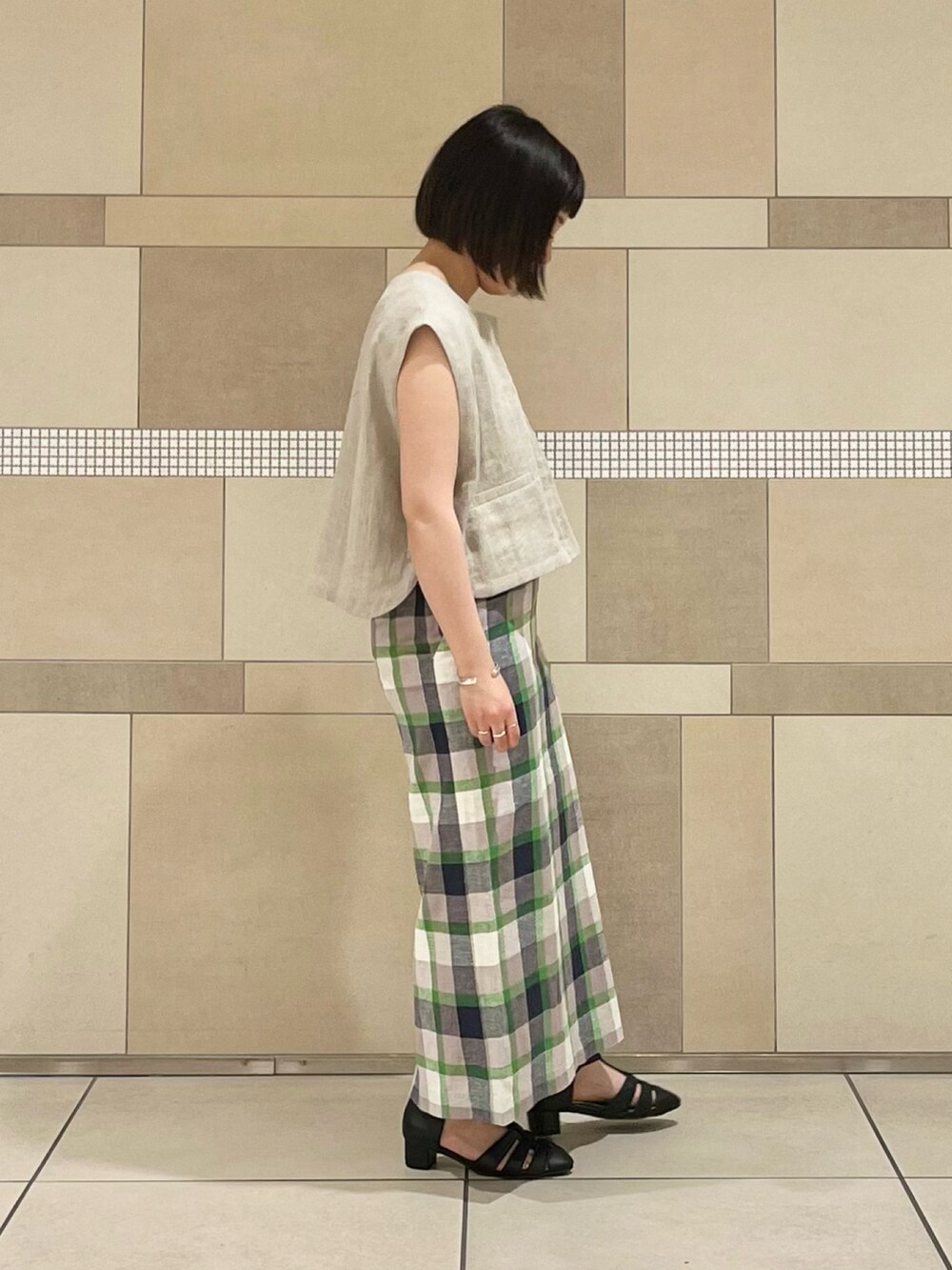 ベージュ系のベスト、ブラック系のタンクトップ、グリーン系のスカートを着用したレディースの春コーディネートの3枚目の写真