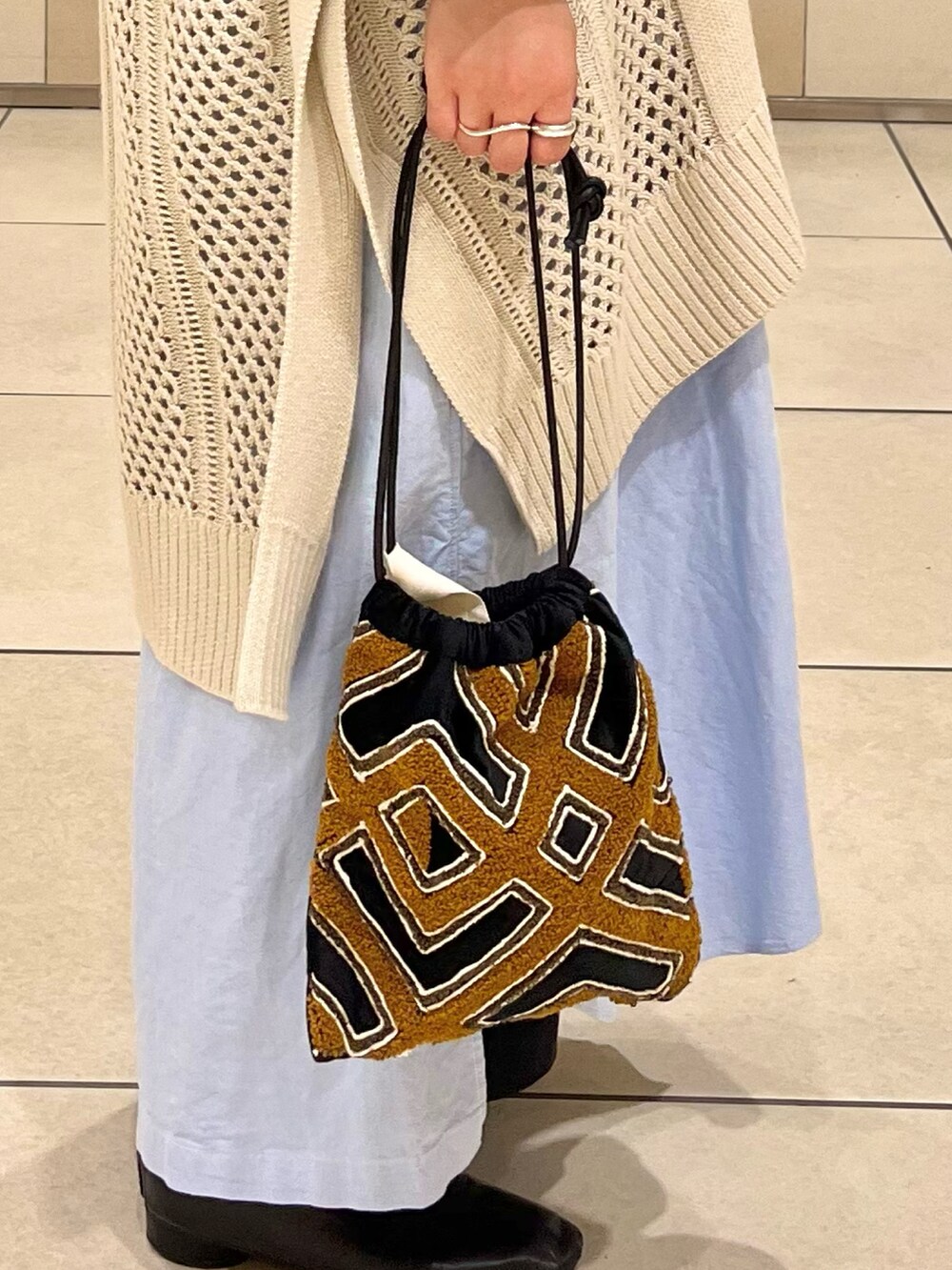 ベージュ系のニット/セーター、ブルー系のワンピース、ブラック系のスカートを着用したレディースの秋コーディネートの5枚目の写真