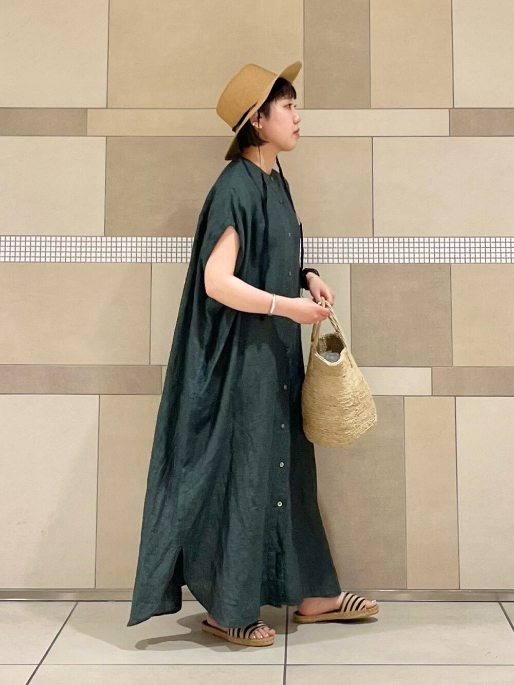 グリーン系のワンピース、ベージュ系のサンダル、ベージュ系のハットを着用したレディースの春コーディネートの3枚目の写真