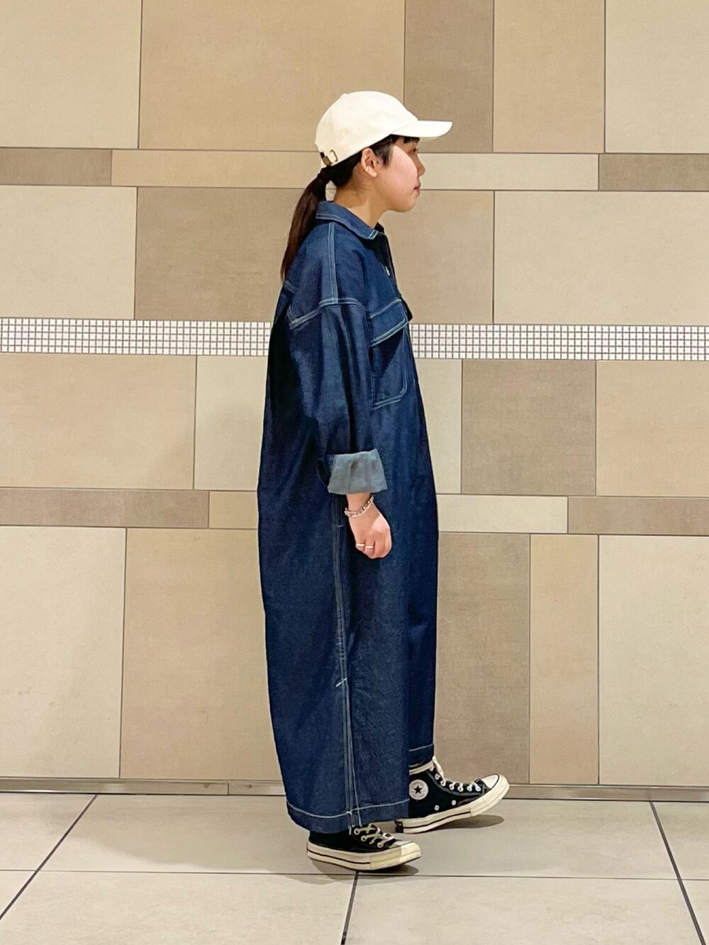 ブルー系のワンピース、グリーン系のTシャツ/カットソー、ホワイト系のキャップを着用したレディースの春コーディネートの3枚目の写真