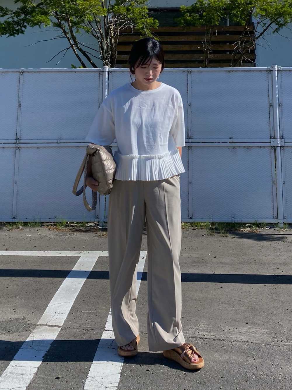 ホワイト系のTシャツ/カットソー、ベージュ系のパンツ、ブラウン系のサンダルを着用したレディースの夏コーディネートの2枚目の写真