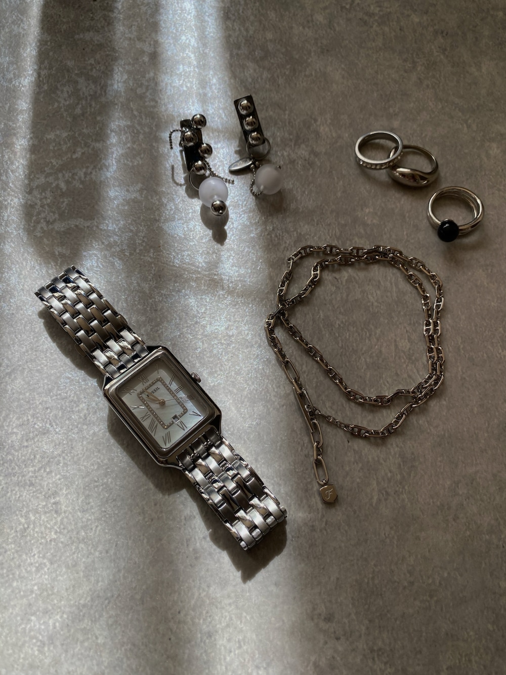 グレー系のスウェットパンツ、ブラック系のブーツ、シルバー系のアナログ腕時計を着用したレディースの秋コーディネートの5枚目の写真