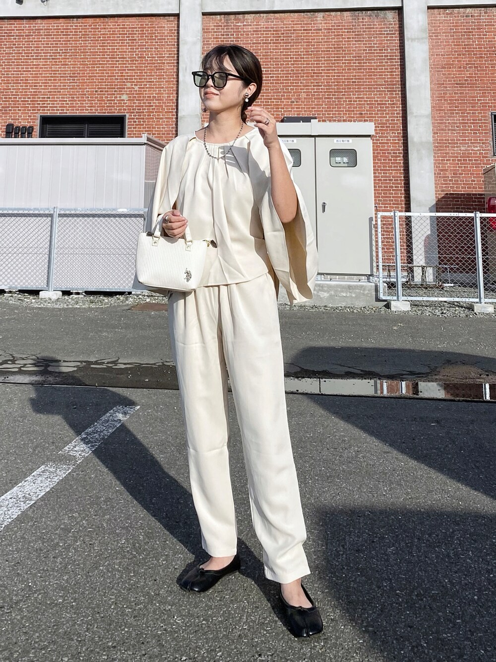 ホワイト系のショルダーバッグ、ブラック系のパンプス、シルバー系のリングを着用したレディースの秋コーディネートの3枚目の写真