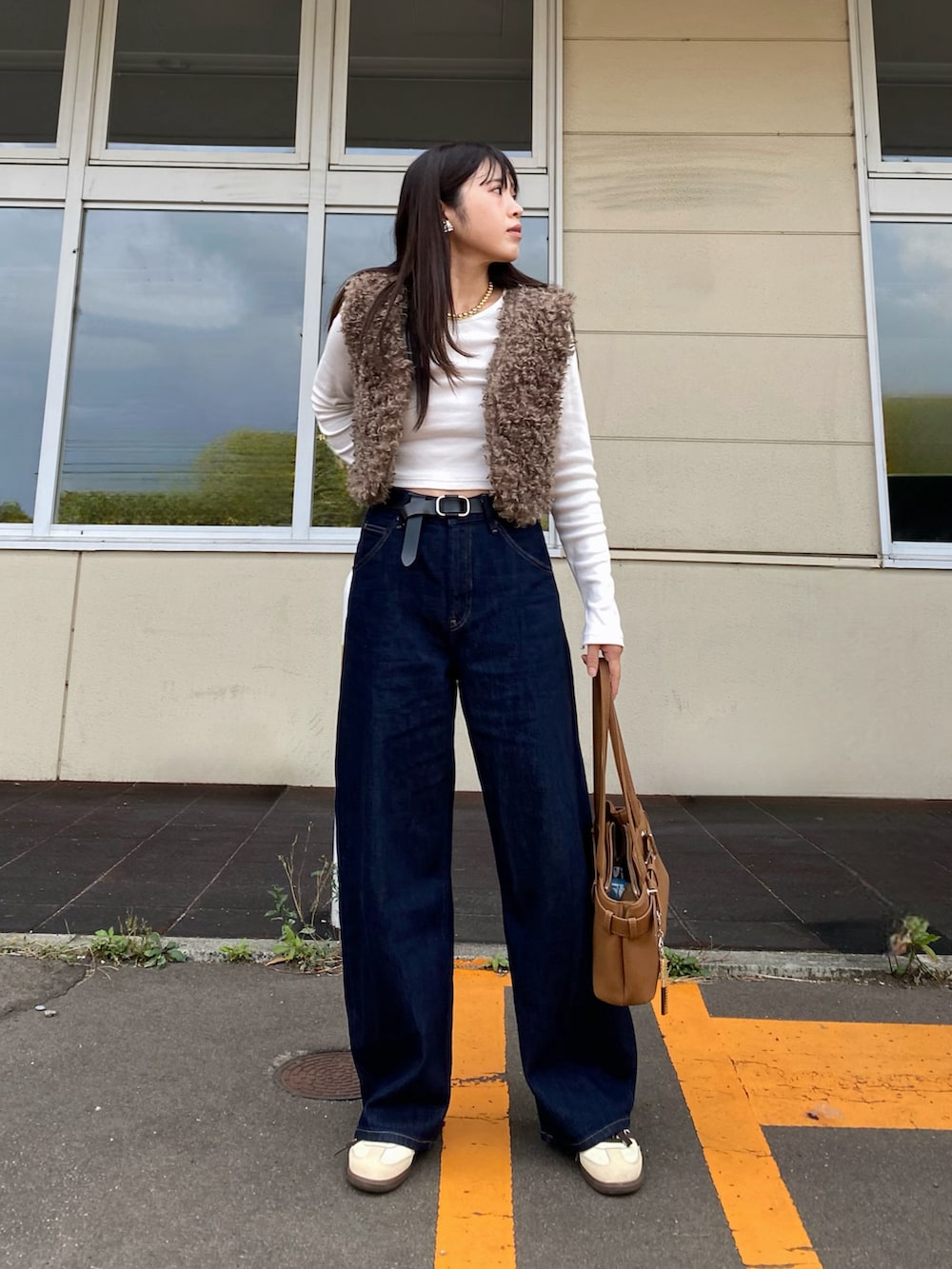 ブラウン系のベスト、ブラウン系のハンドバッグ、ベージュ系のスニーカーを着用したレディースの秋コーディネートの4枚目の写真