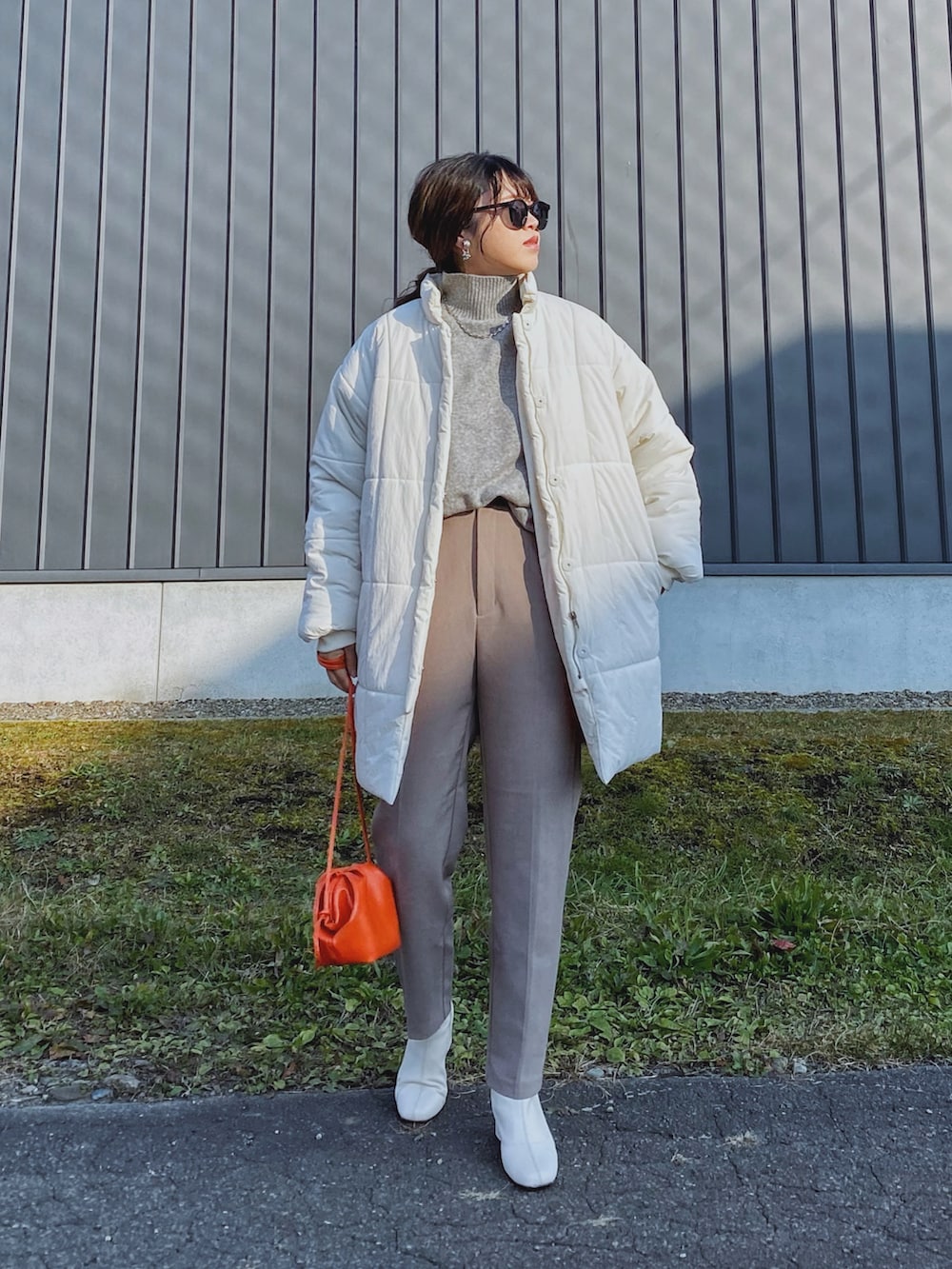 ホワイト系のダウンジャケット/コート、オレンジ系のショルダーバッグ、グレー系のニット/セーターを着用したレディースの秋コーディネートの2枚目の写真