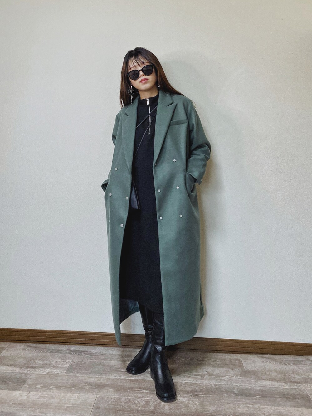 グリーン系のチェスターコート、ブラック系のワンピース、ブラック系のブーツを着用したレディースの秋コーディネートの2枚目の写真