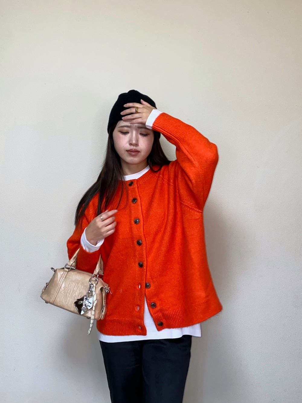 オレンジ系のニット/セーター、ブラック系のその他パンツ、ベージュ系のボストンバッグを着用したレディースの秋コーディネートの4枚目の写真