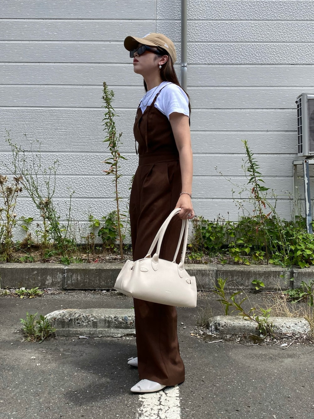 ブラック系のボストンバッグ、ベージュ系のキャップを着用したレディースの夏コーディネートの2枚目の写真