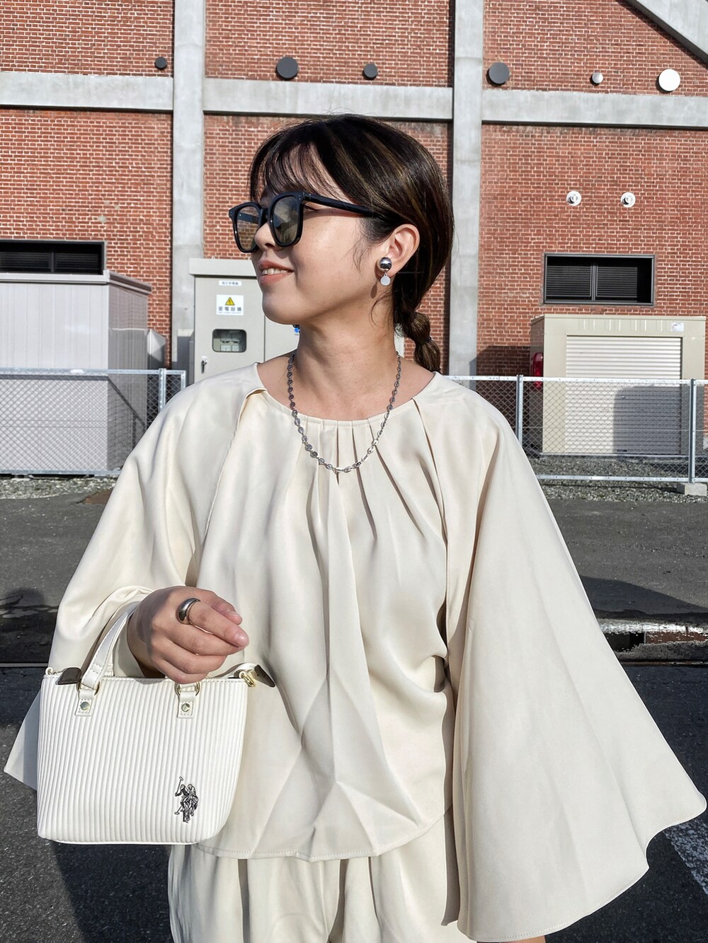 ホワイト系のショルダーバッグ、ブラック系のパンプス、シルバー系のリングを着用したレディースの秋コーディネートの5枚目の写真