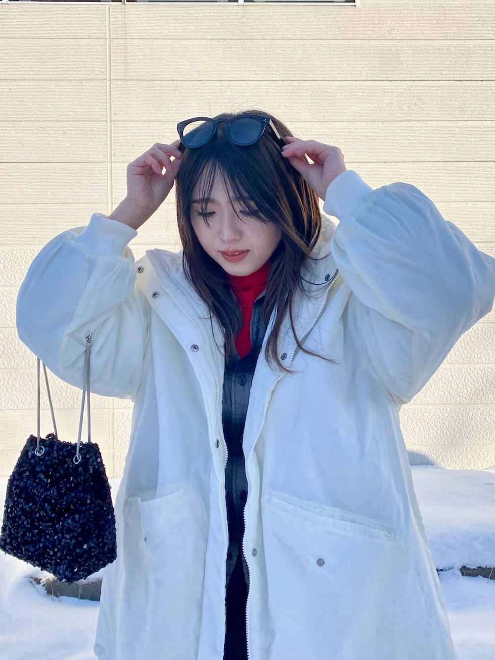 ホワイト系のダウンジャケット/コート、レッド系のニット/セーター、ブラック系のシャツ/ブラウスを着用したレディースの冬コーディネートの2枚目の写真