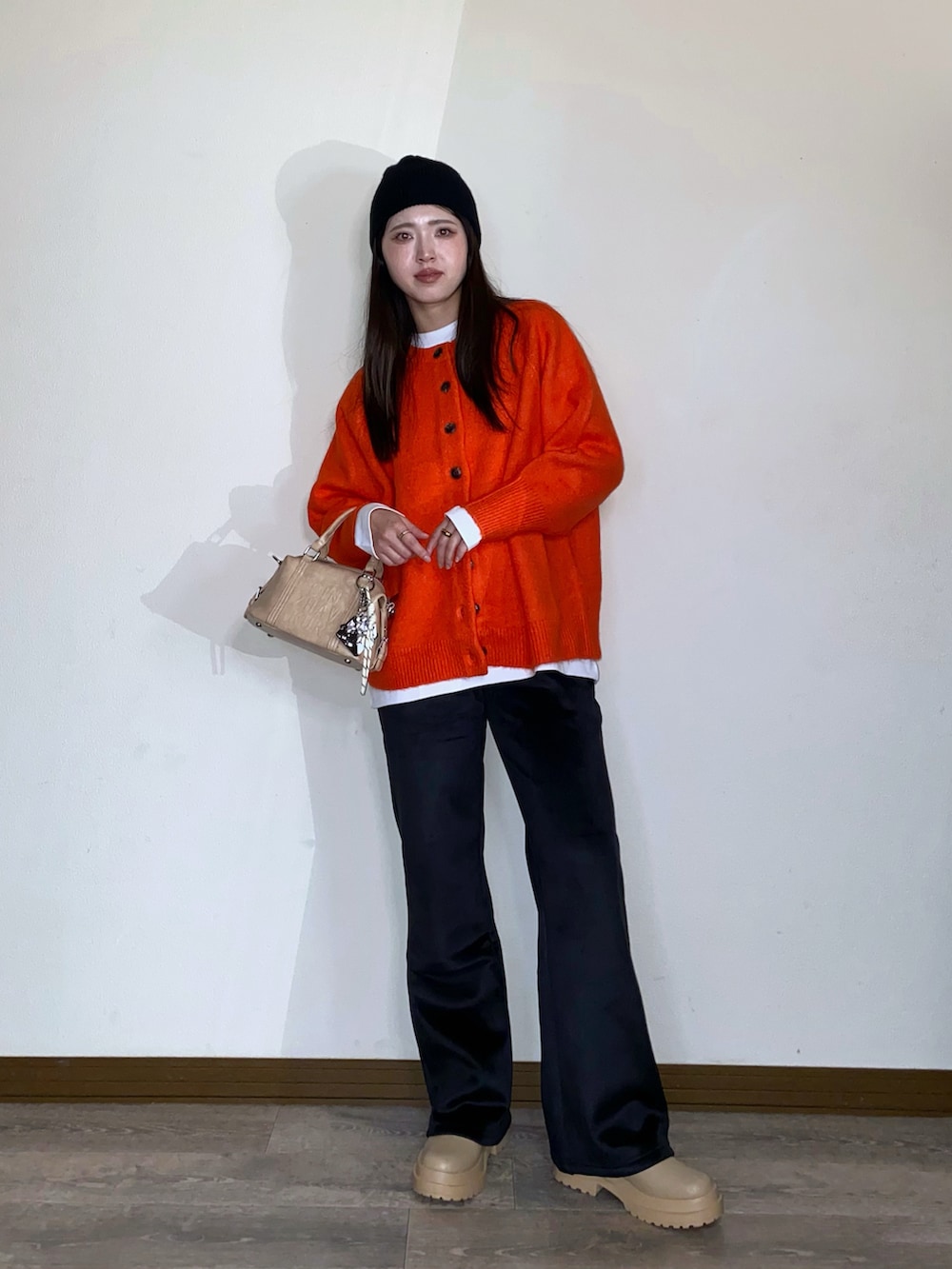 オレンジ系のニット/セーター、ブラック系のその他パンツ、ベージュ系のボストンバッグを着用したレディースの秋コーディネートの3枚目の写真