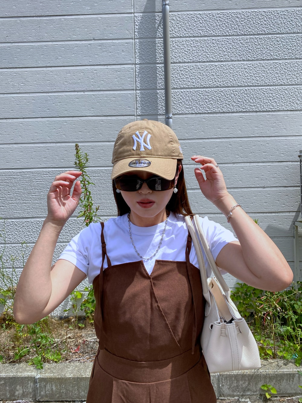 ブラック系のボストンバッグ、ベージュ系のキャップを着用したレディースの夏コーディネートの3枚目の写真