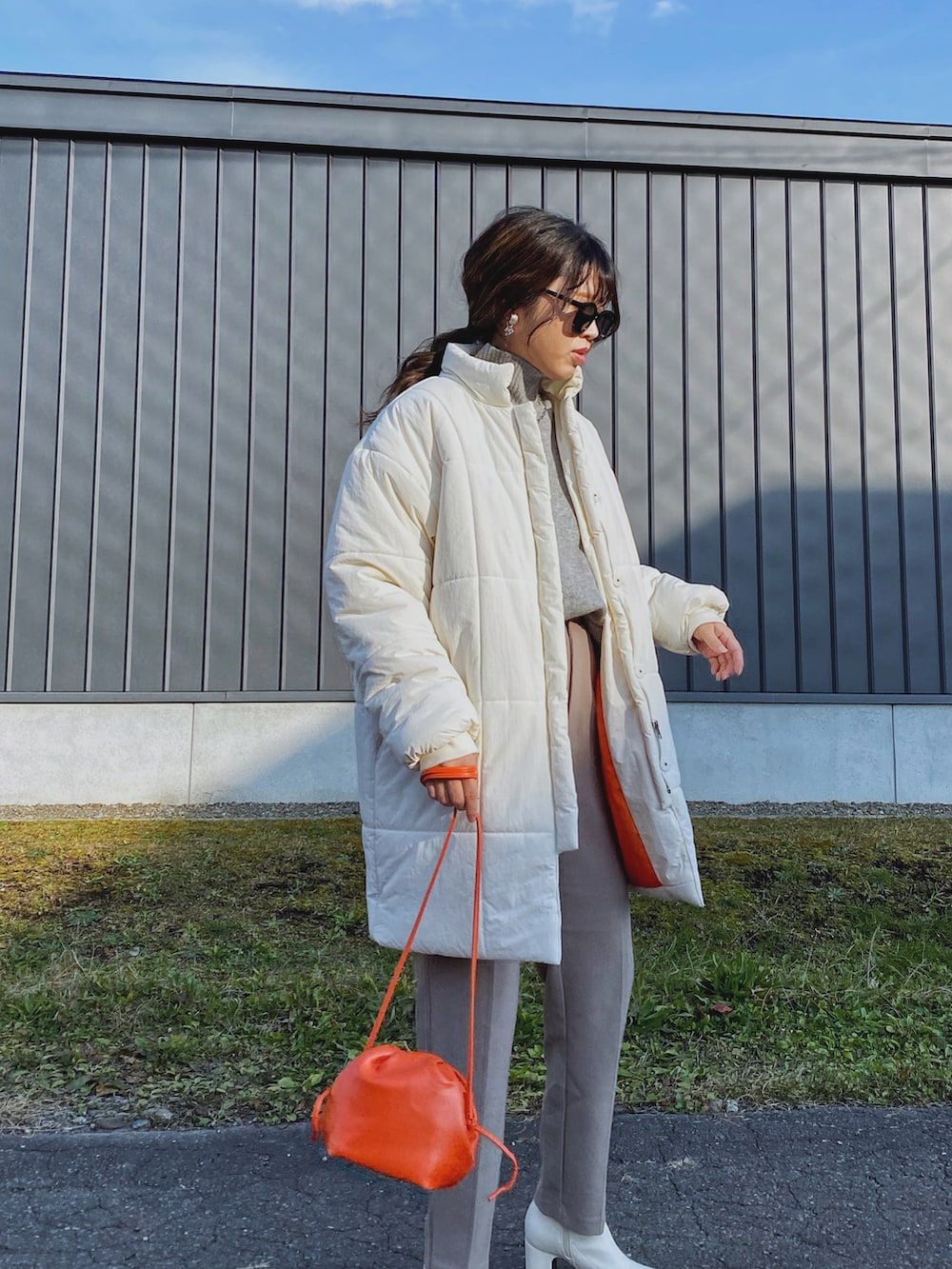 ホワイト系のダウンジャケット/コート、オレンジ系のショルダーバッグ、グレー系のニット/セーターを着用したレディースの秋コーディネートの5枚目の写真