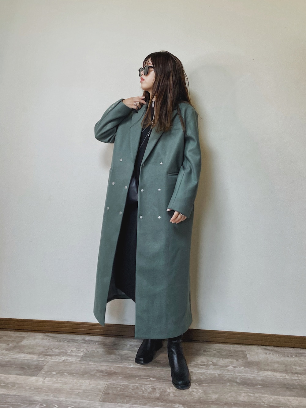 グリーン系のチェスターコート、ブラック系のワンピース、ブラック系のブーツを着用したレディースの秋コーディネートの4枚目の写真