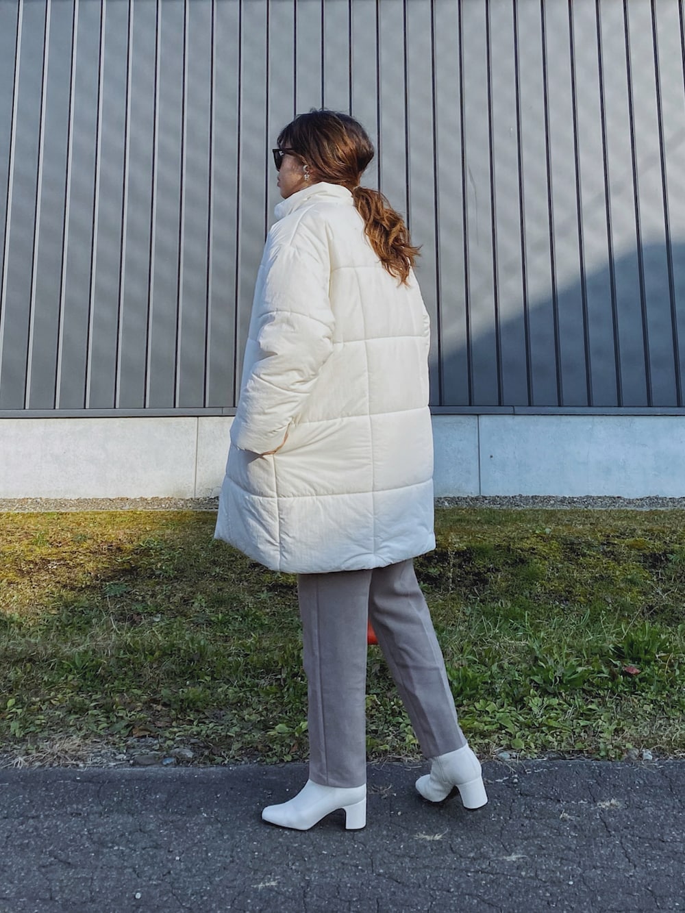 ホワイト系のダウンジャケット/コート、オレンジ系のショルダーバッグ、グレー系のニット/セーターを着用したレディースの秋コーディネートの3枚目の写真