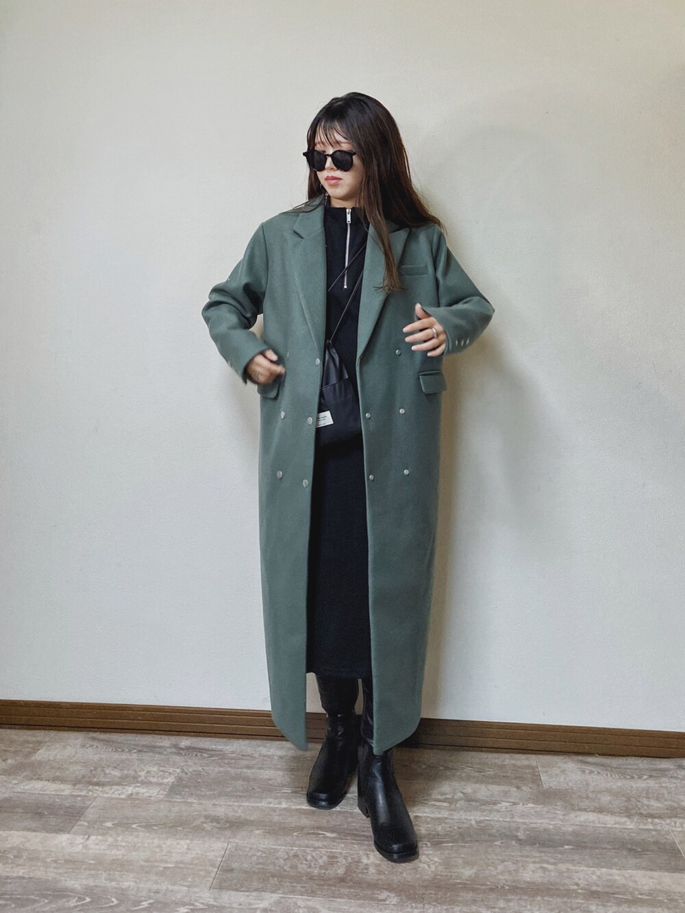 グリーン系のチェスターコート、ブラック系のワンピース、ブラック系のブーツを着用したレディースの秋コーディネートの3枚目の写真