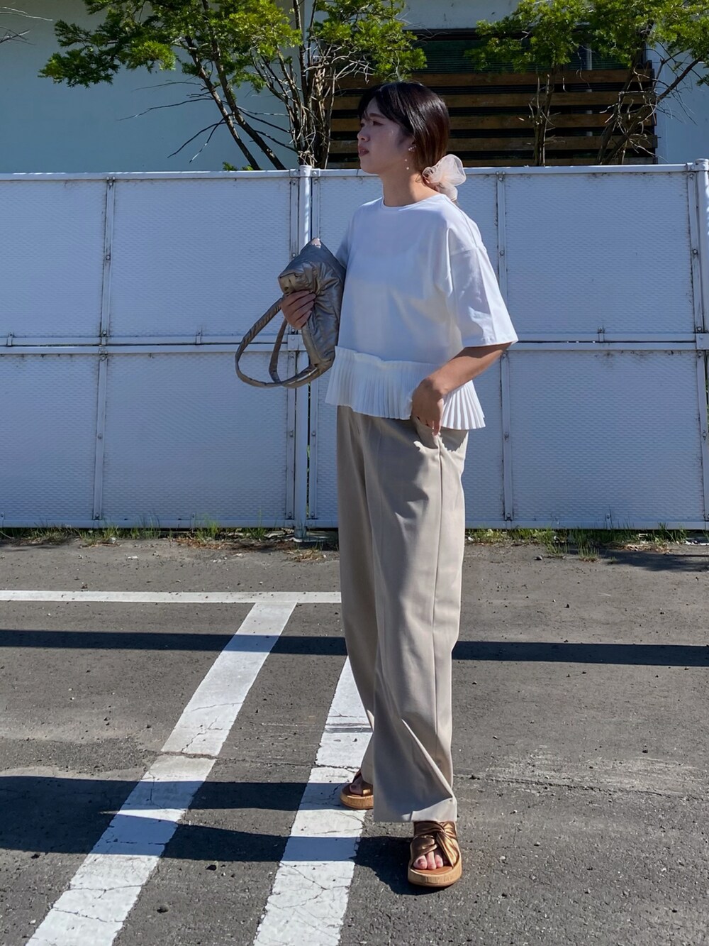 ホワイト系のTシャツ/カットソー、ベージュ系のパンツ、ブラウン系のサンダルを着用したレディースの夏コーディネートの3枚目の写真