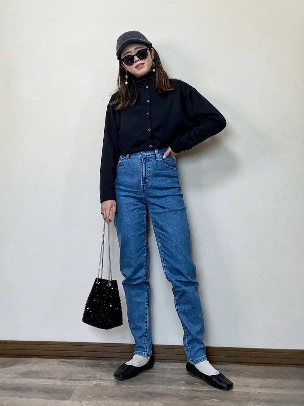 ブルー系のデニムパンツ、グレー系のニット/セーター、シルバー系のイヤリングを着用したレディースの冬コーディネートの2枚目の写真