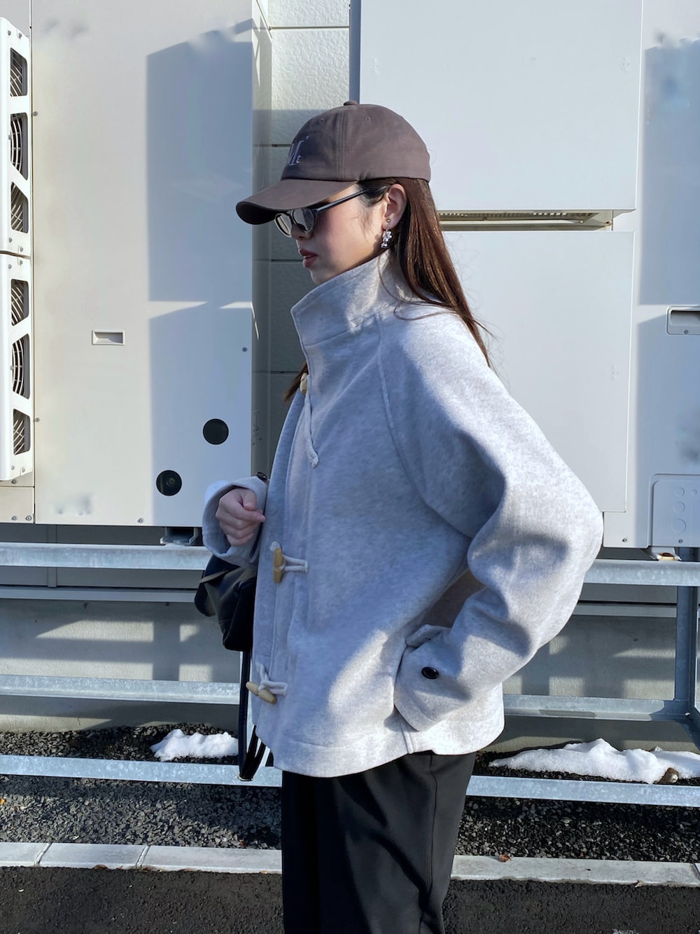 ブラック系のブーツ、ホワイト系のダッフルコート、ブラック系のハンドバッグを着用したレディースの秋コーディネートの3枚目の写真