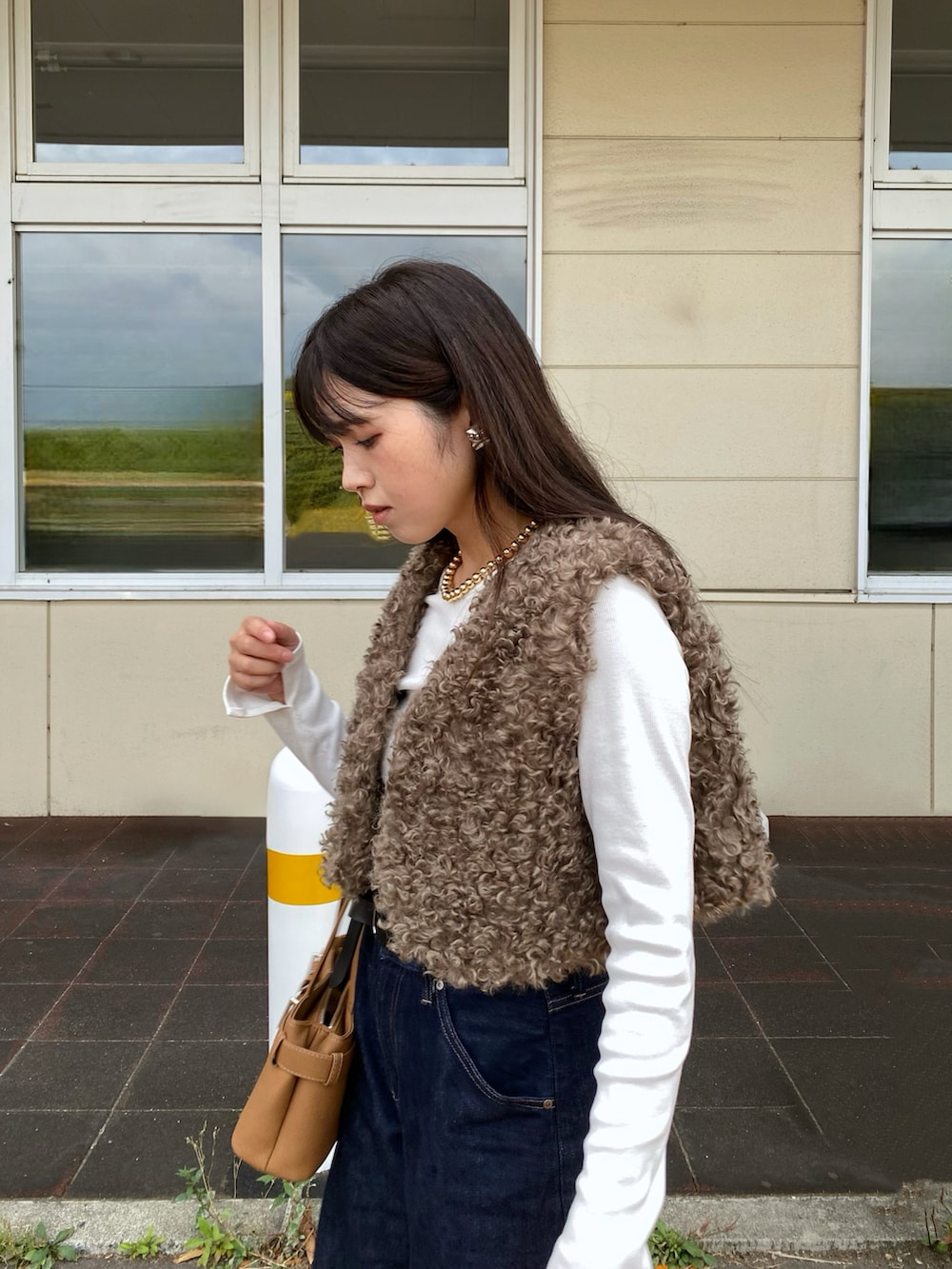 ブラウン系のベスト、ブラウン系のハンドバッグ、ベージュ系のスニーカーを着用したレディースの秋コーディネートの5枚目の写真