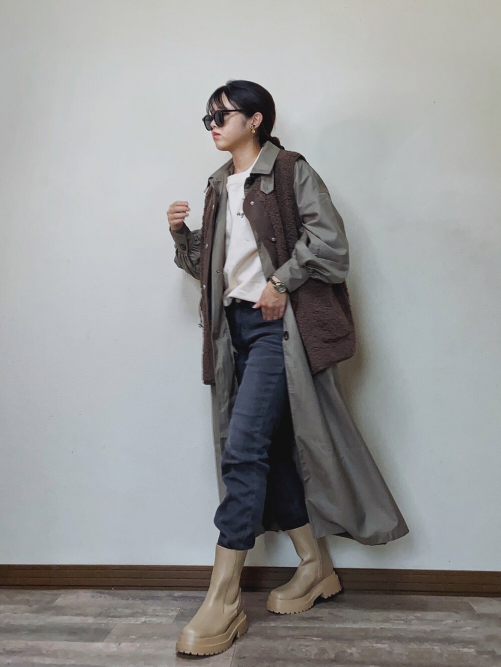 グレー系のトレンチコート、ホワイト系のスウェット、グレー系のデニムパンツを着用したレディースの冬コーディネートの2枚目の写真