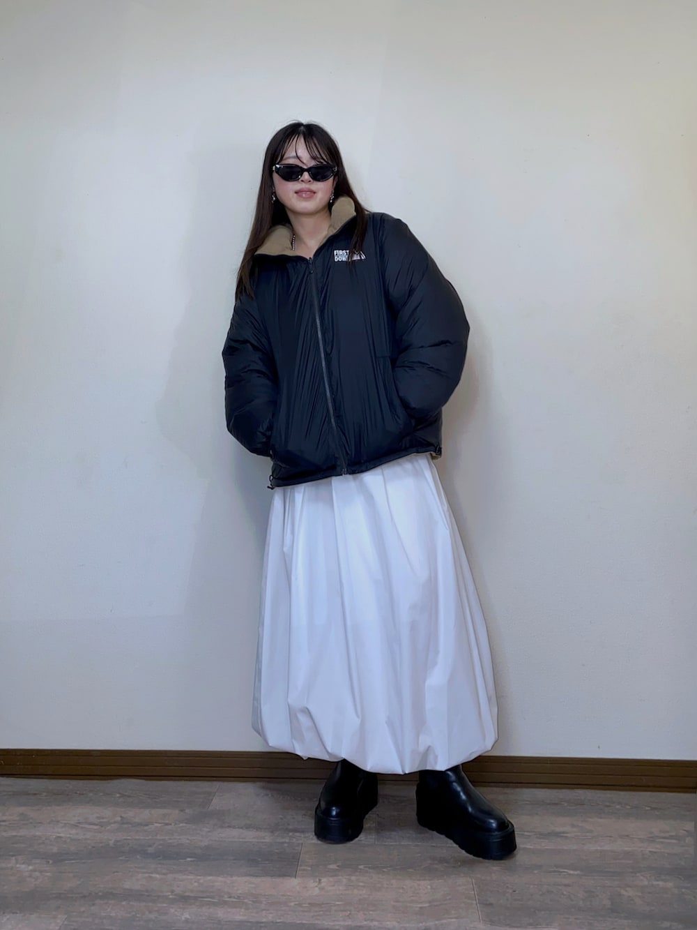 ベージュ系のダウンジャケット/コート、ホワイト系のスカート、ブラック系のブーツを着用したレディースの冬コーディネートの2枚目の写真