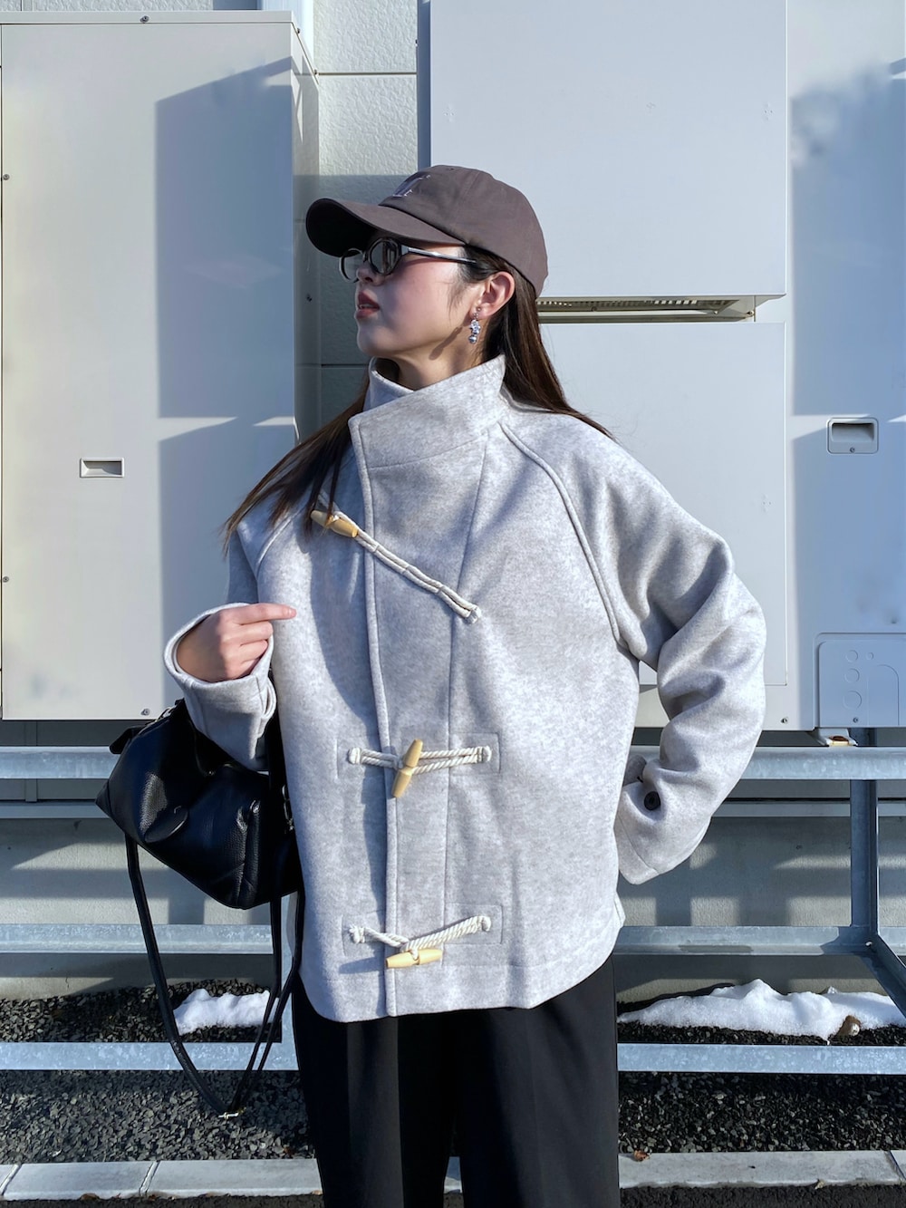 ブラック系のブーツ、ホワイト系のダッフルコート、ブラック系のハンドバッグを着用したレディースの秋コーディネートの2枚目の写真