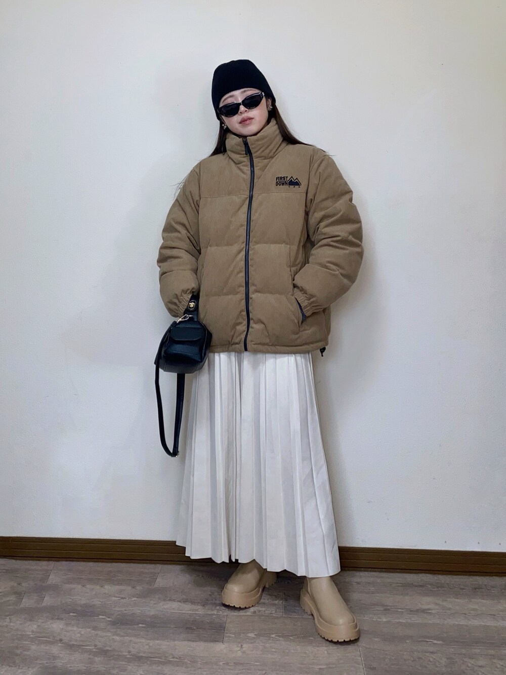ベージュ系のダウンジャケット/コート、ホワイト系のスカート、ブラック系のハンドバッグを着用したレディースの秋コーディネートの2枚目の写真