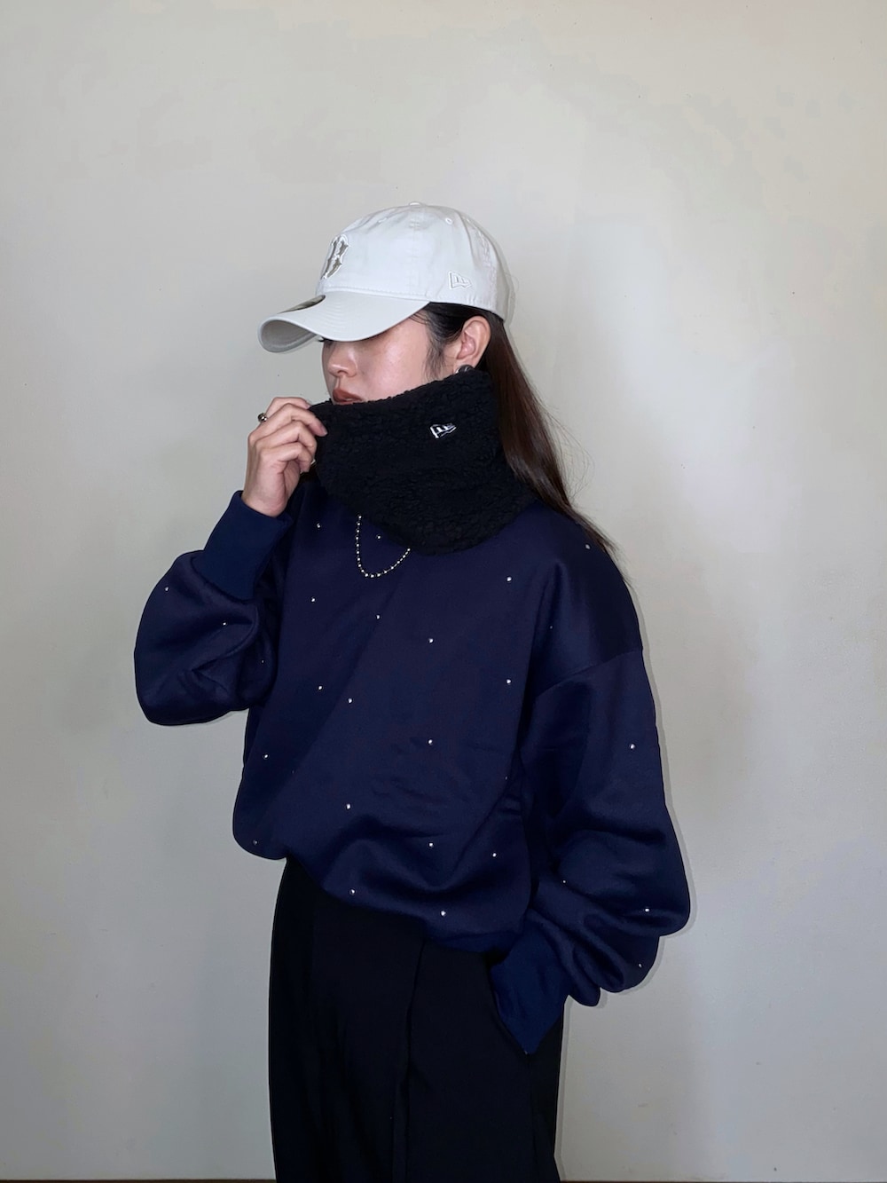 ブルー系のスウェット、ベージュ系のキャップ、ブラック系のネックウォーマー/スヌードを着用したレディースの冬コーディネートの2枚目の写真