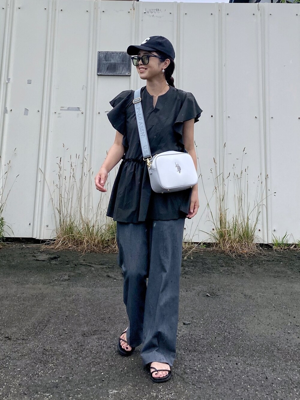 ホワイト系のショルダーバッグ、グレー系のパンツ、ブラック系のラッシュガードを着用したレディースの夏コーディネートの2枚目の写真