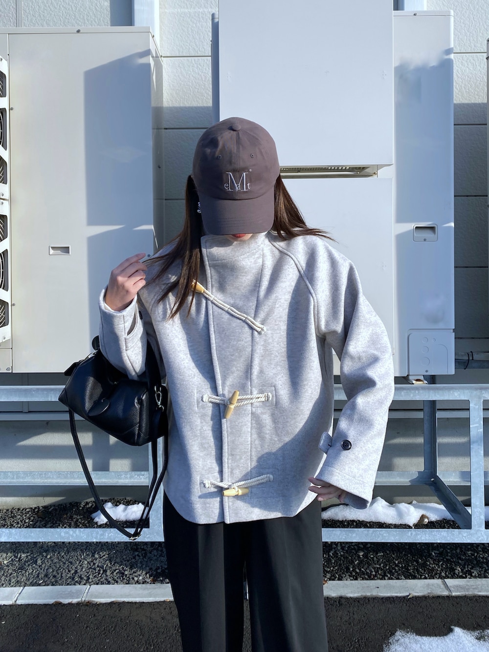 ブラック系のブーツ、ホワイト系のダッフルコート、ブラック系のハンドバッグを着用したレディースの秋コーディネートの5枚目の写真